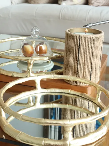 Our round bamboo-style mirror tray, styled with a cloche and a candle. The mirrored surface beautifully reflects light, creating a warm and inviting atmosphere.
