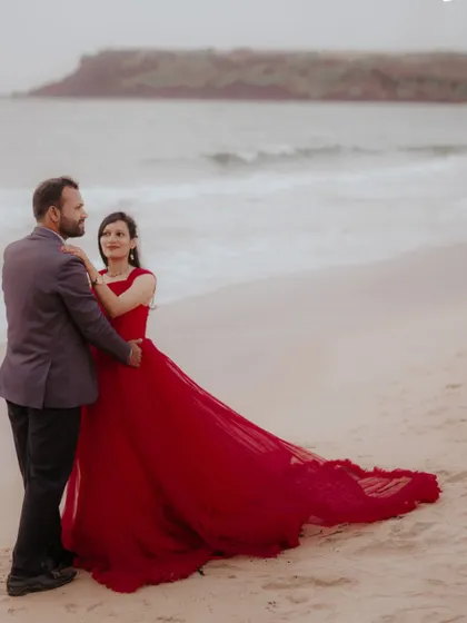 A romantic walk on the beach. The red trail gown flows beautifully behind the couple, creating a classic and timeless pre-wedding image.