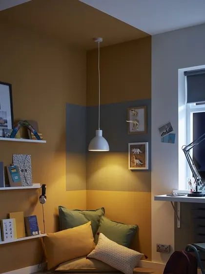 We created a cozy reading corner using blocks of mustard yellow and grey. This colour blocking technique adds warmth and defines the small space, making it feel intentional and inviting.