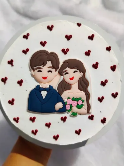 An anniversary bento cake with a cute, edible couple topper and tiny red hearts.