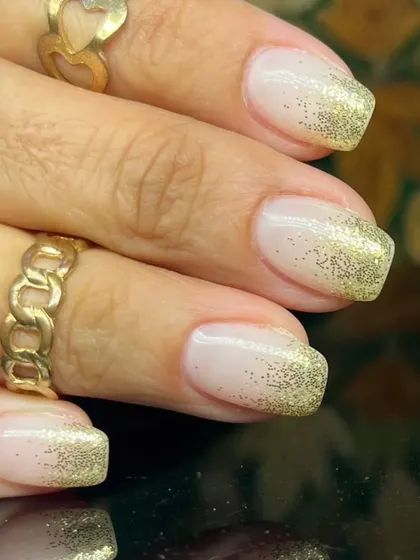 A classic French manicure with a twist, featuring a beautiful gold glitter fade from the tips.