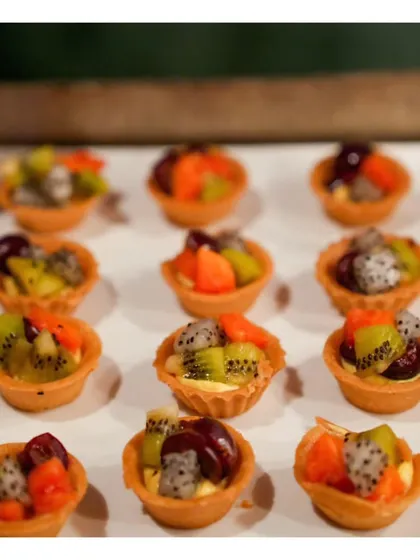 A close-up of our delicate mini fruit tartlets, filled with creamy custard and topped with a colourful assortment of fresh seasonal fruits.