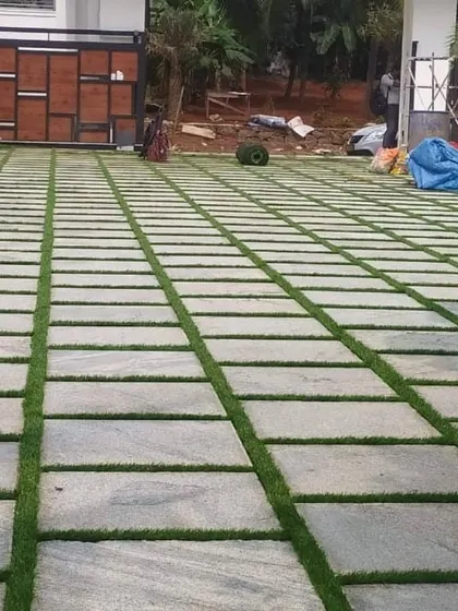 A work-in-progress shot of a large driveway. The stone pavers have been laid, and the gaps are now ready to be filled with soil and grass seed or sod to create the final green-striped effect.