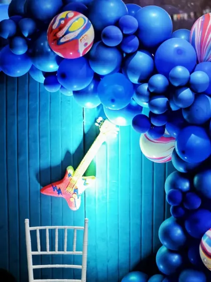 Another angle of the Rockstar party decor, showing a vibrant blue balloon arch over a textured blue wall with a light-up guitar. I use color and light to create a dynamic atmosphere.