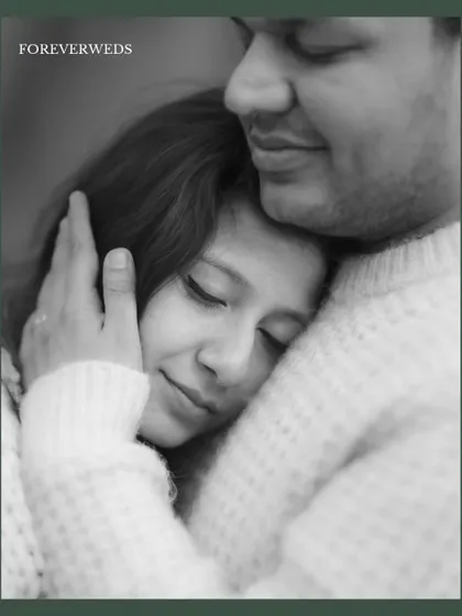 A close-up black and white portrait showing Sayantani resting peacefully in Piyush's embrace. This image conveys a profound sense of safety, comfort, and trust.