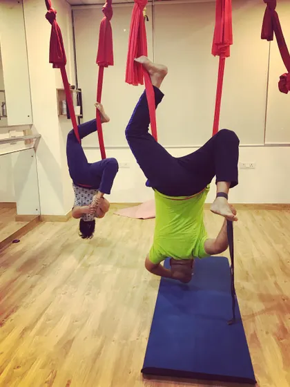 Two students explore an inverted pigeon pose. Even in a group class, everyone works at their own pace and level, modifying poses to suit their body.