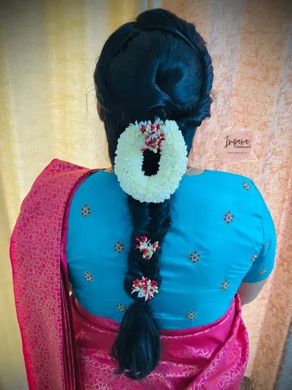 A neat and traditional braided bun, adorned with a jasmine 'gajra'. This hairstyle is perfect for a classic Muhurtham look, keeping the hair elegantly off the face.