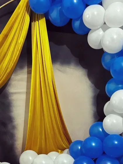 A close-up detail of one of our simple home party setups. This image highlights the combination of a blue and white balloon arch on a ring frame, accented with a draped gold cloth for a touch of elegance.