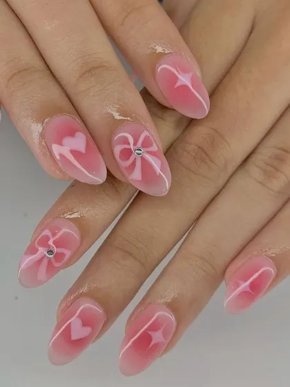 This "aura" nail set in pink is giving all the coquette vibes with its hand-painted bows, hearts, and stars.