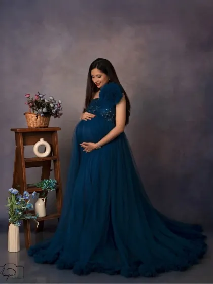 A quiet moment of connection, as she looks down at her bump. The simple studio setup allows her emotion to be the focus.