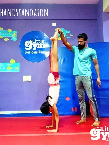 An instructor provides a gentle assist, helping this grade schooler find her balance and hold a perfect handstand.