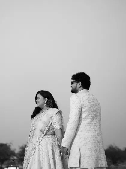 A black and white portrait of the couple, holding hands against the vast desert sky.