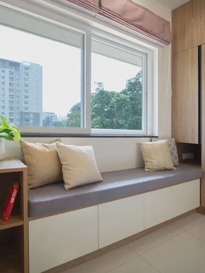 This cozy window seat in a guest room provides comfortable seating and includes built-in storage underneath. It is a practical way to add function to a small space while creating a perfect spot to relax.