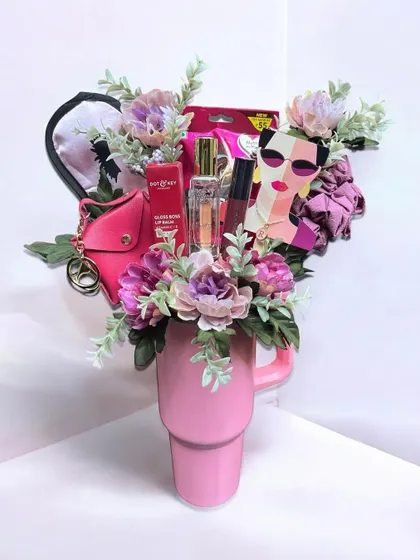 This unique gift is a bouquet of goodies arranged inside a large pink tumbler. It's a creative and modern alternative to a traditional flower bouquet, filled with makeup, accessories, and treats.