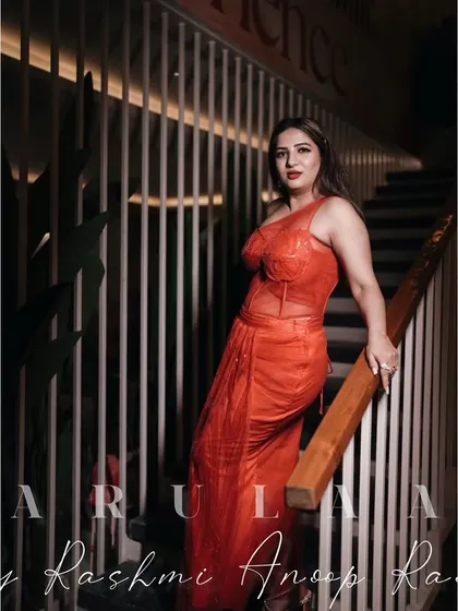 The gorgeous Kaavya Shah wearing a custom-designed red-orange draped saree with a corset-style bodice for a Christmas event.
