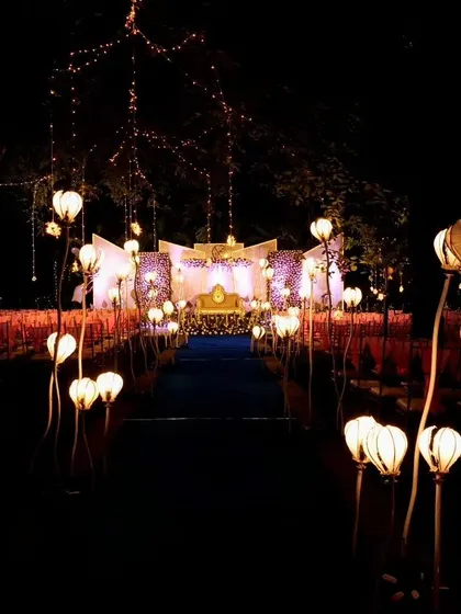 An aisle illuminated by unique, flower-shaped floor lamps leading to the main stage. This custom lighting installation adds a fantastical and artistic element to the wedding decor, making the walk to the stage truly special.