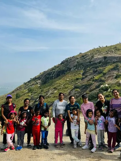 Mothers and children posing for a group photo with a beautiful mountain in the background.