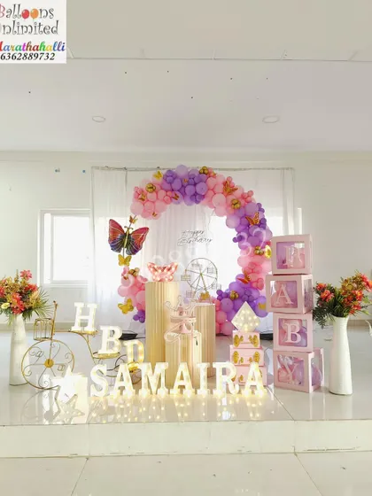 A full stage view of a butterfly theme in a large hall, showing how I use balloon arches and themed props to fill a space beautifully.