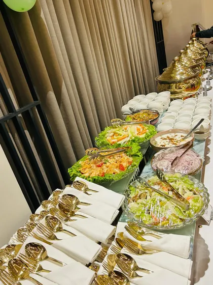 This catering spread for a corporate event features a fresh salad bar alongside hot main courses. We ensure every element, from the cutlery to the serving bowls, is arranged for a clean and professional presentation.