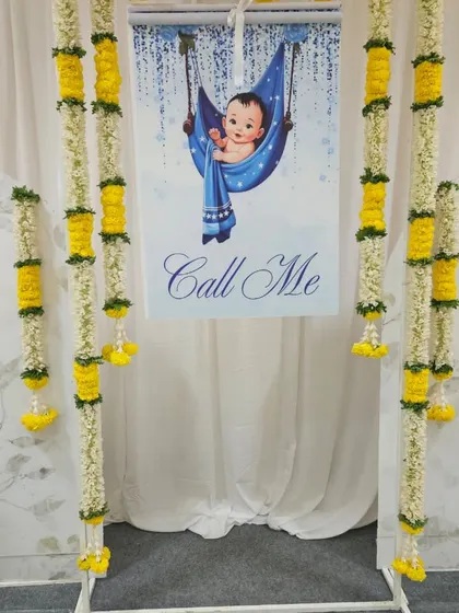The "Call Me" banner is a sweet and playful touch for a naming ceremony, building anticipation for the big reveal. We framed it with traditional flower garlands to blend it seamlessly into the overall decor.