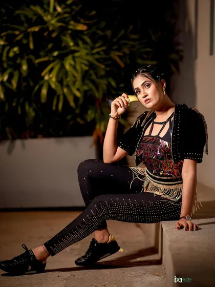An edgy, rock-inspired look. The embellished jacket with fringe and fitted pants create a unique and powerful style, captured in an outdoor night setting.