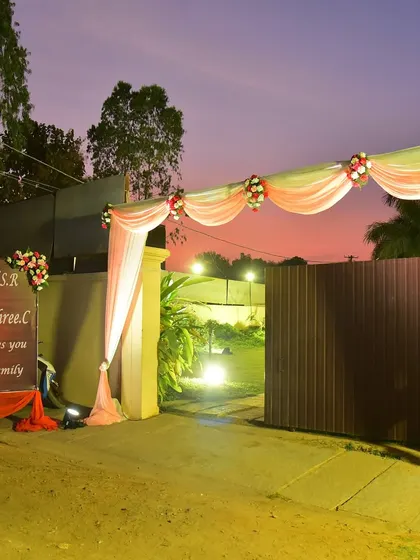 A simple and elegant entrance for a wedding at dusk, with a custom welcome board and draped archway.