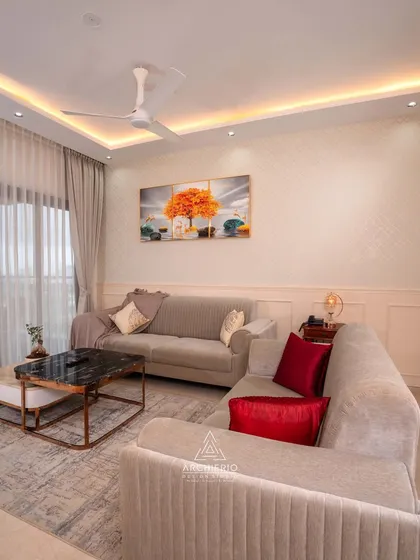A cozy living room with a comfortable L-shaped sofa and a pop of color from the red cushions. The space is simple, elegant, and perfect for everyday living.
