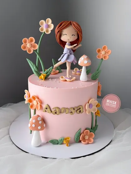 A lovely flower girl cake. This pink cake is decorated with a garden of handcrafted flowers and mushrooms, with a sweet fairy figurine dancing in the middle.