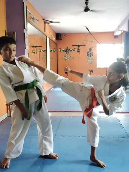 Two students practice a controlled kick, learning about distance and timing in a safe environment.