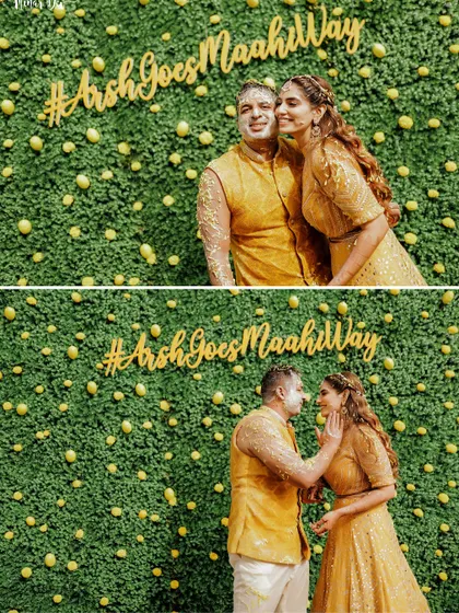 The "after" shot! The couple covered in haldi, posing against a custom lemon and foliage photo wall with their wedding hashtag.