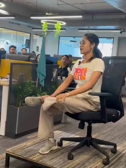 Demonstrating a seated hip-opening stretch on an office chair, a key exercise to relieve tightness from sitting.