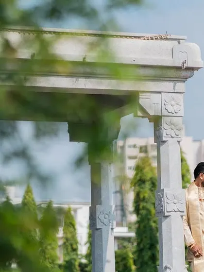 A quiet moment of togetherness, framed by greenery and classical architecture. This image balances the grandeur of the location with the simple, serene bond between the couple.