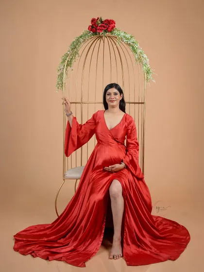 A graceful portrait of the mom-to-be seated in our golden birdcage prop. This setup creates a whimsical and romantic atmosphere.