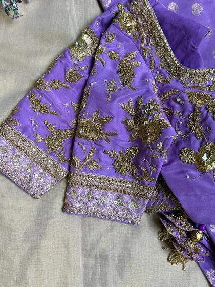 An elegant purple blouse with intricate golden Zari embroidery.
