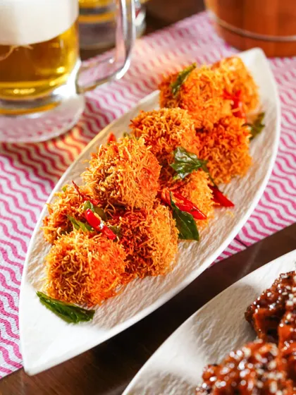 Crispy fried appetizers served on a white platter, with a mug of beer in the background. This shot captures the perfect pairing for an Oktoberfest celebration.