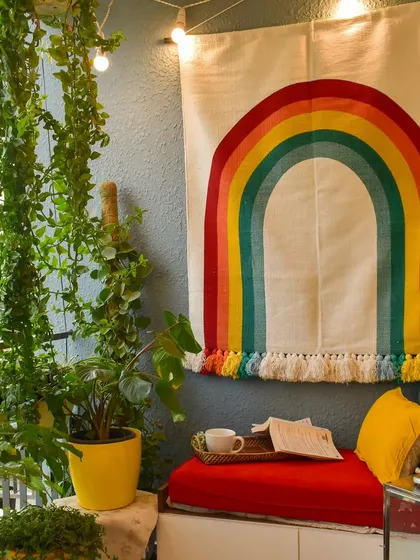 My tiny balcony styled for spring with a cheerful rainbow tapestry. It’s a happy and colorful spot to enjoy a cup of coffee.