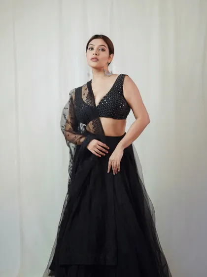 A strong and confident pose in the black lehenga. This shot highlights the modern design of the blouse and the overall powerful aesthetic of the outfit.