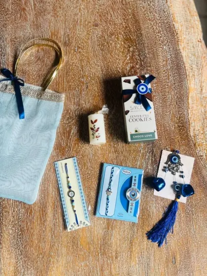 The contents of the blue evil-eye themed Rakhi bag, including matching rakhis, a candle, and cookies.