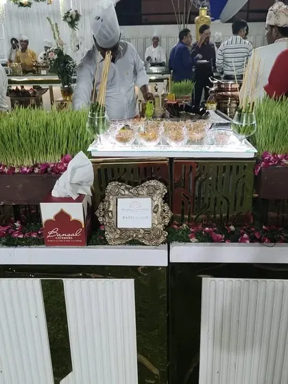 A chef preparing a Bhel Puri station, a popular live chaat counter, set against a backdrop of wheatgrass decor.