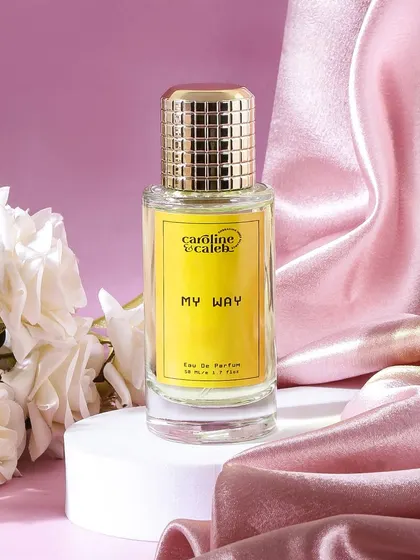 A classic and romantic perfume shot, styled with white roses and a pink satin drape. This composition is timelessly elegant and speaks to the fragrance's sophisticated character.