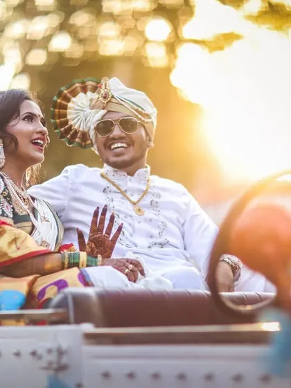 A stylish, sun-kissed photo of the couple enjoying a ride in their open-top wedding car. The flare from the sun adds a cinematic quality.