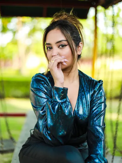 A close-up, pensive portrait of the model in the blue bodysuit, highlighting her makeup and the top's unique texture.