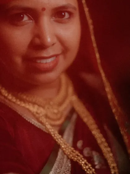 A warm, artistic close-up portrait of the bride. The soft, reddish lighting creates an intimate and timeless feel.