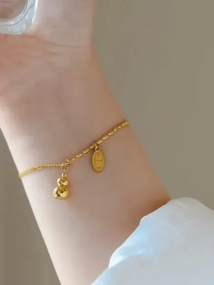 A charming gold-toned bracelet with a gourd-shaped charm and an engraved oval charm. This unique piece is available for just 15 shekels.
