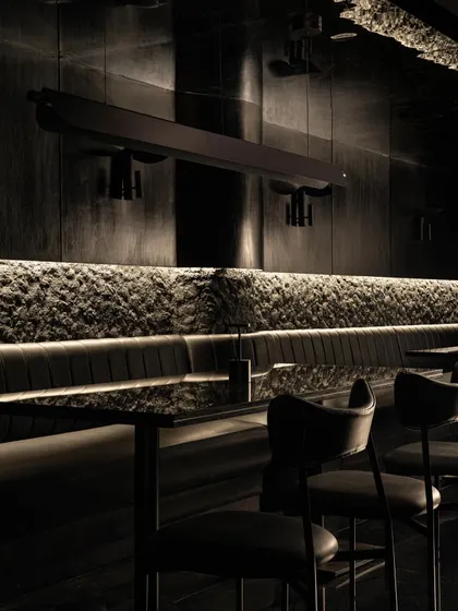 Details of the seating at Lair, where rough, rock-like textures meet smooth leather upholstery. This tactile contrast is central to the bar's sensory narrative.