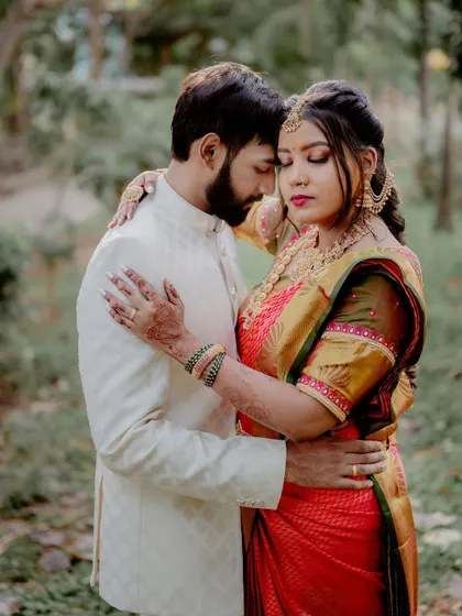A tender moment between the couple. The focus is on their embrace and the rich details of the bride's traditional attire, from the texture of the saree to her intricate jewelry.