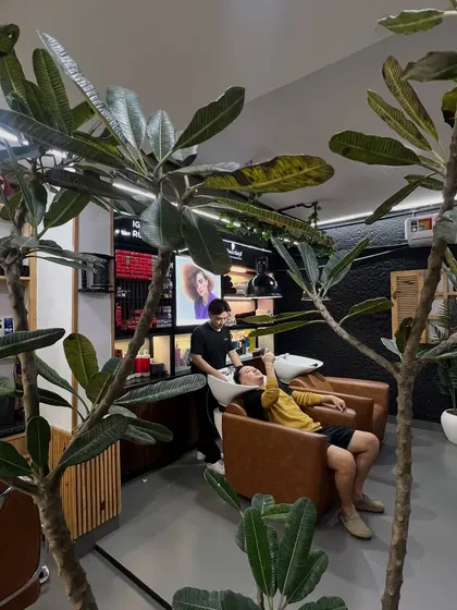 A client enjoying a relaxing hair wash. The greenery and modern design of the salon contribute to a calming and rejuvenating atmosphere.