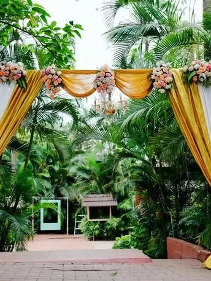 A daytime entrance arch decorated with yellow and white drapes and florals, offering a bright and cheerful welcome to wedding guests.