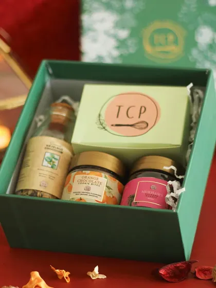 Our Pradan 2.0 hamper is a compact yet delightful gift. This elegant green box contains a loaf cake, mukhwas, cookie bites, and a mini granola bottle.