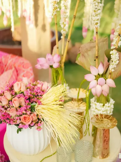 A beautiful floral detail from our 'Serene Vibes' Mehendi. Pink lotuses and roses are arranged in modern white vases, creating a perfect blend of traditional flowers and contemporary styling.